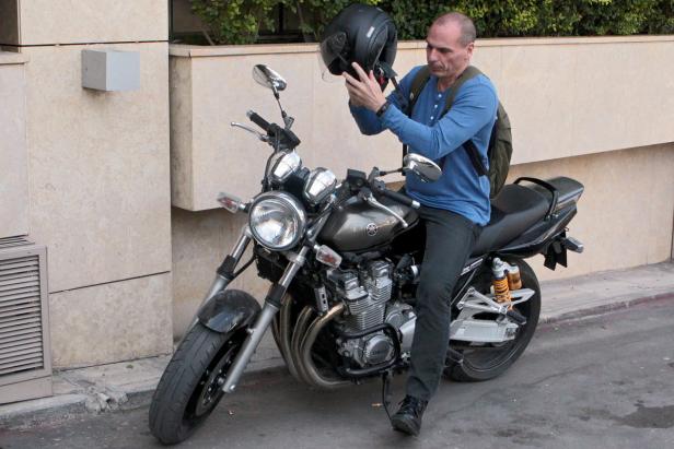 Ein Mann sitzt auf einem Motorrad und setzt einen Helm auf.