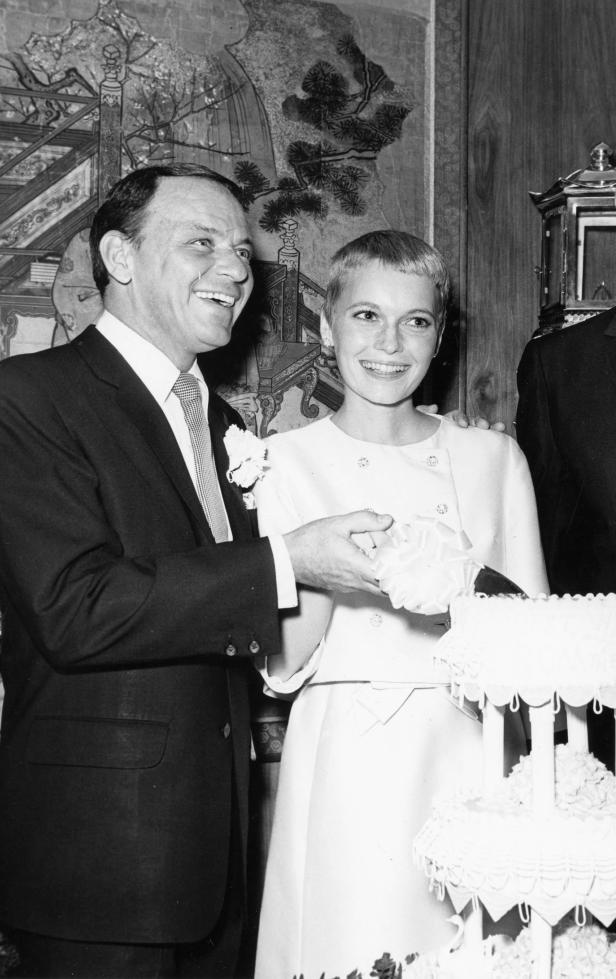 Frank Sinatra und Mia Farrow schneiden gemeinsam eine Hochzeitstorte an.