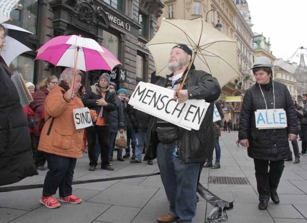 Menschen demonstrieren mit Schildern, auf denen „Menschen sind alle“ steht.