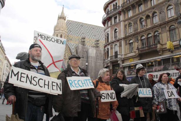 Eine Gruppe von Menschen demonstriert mit Schildern für Menschenrechte in Wien.