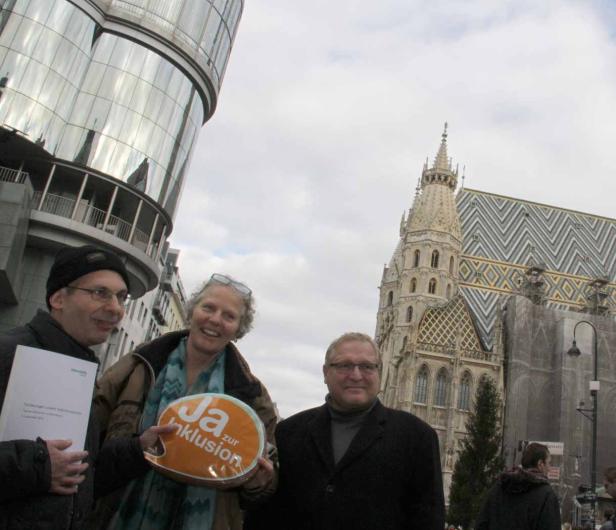 Drei Personen halten ein Schild mit der Aufschrift „Ja zur Inklusion“ vor dem Stephansdom in Wien.