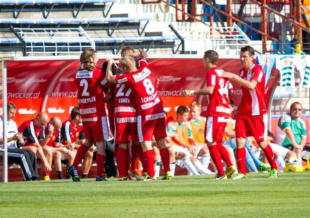 Eine Gruppe Fußballspieler in roten Trikots feiert ein Tor.