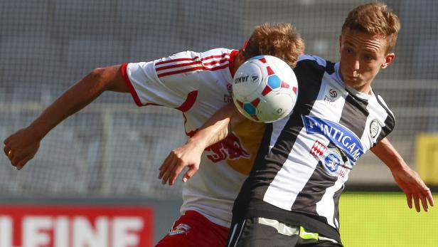 Zwei Fußballspieler kämpfen um den Ball.