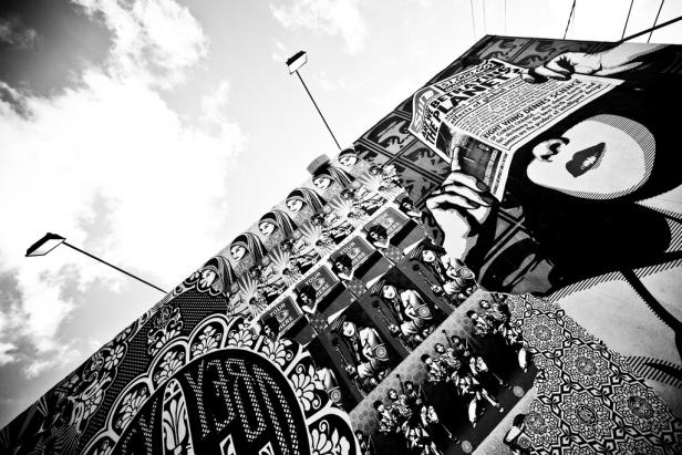 Ein Schwarz-Weiß-Foto einer Wand mit verschiedenen Kunstwerken und politischen Botschaften.