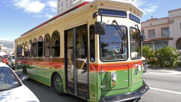 Ein grüner und beiger Trolleybus der Coral Gables steht auf einer Straße.