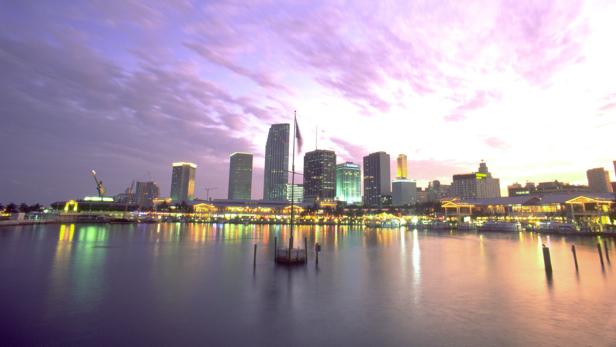 Die Skyline von Miami spiegelt sich im Wasser bei Sonnenuntergang.