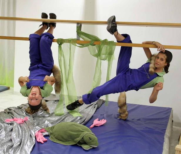 Zwei Mädchen in Kostümen mit Fuchsschwänzen turnen an einer Ballettstange.