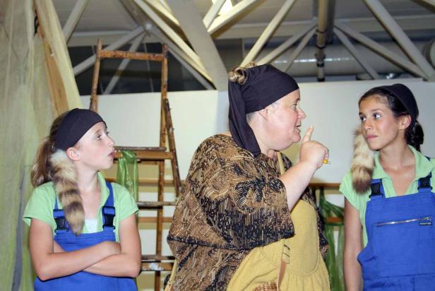 Eine Frau ermahnt zwei Mädchen in Kostümen während einer Theateraufführung.