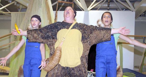 Eine Frau und zwei Kinder stehen mit ausgestreckten Armen auf einer Bühne.