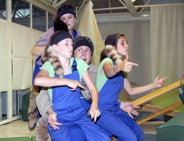 Eine Gruppe von Schauspielern in Kostümen auf einer Bühne, die in verschiedene Richtungen zeigen.