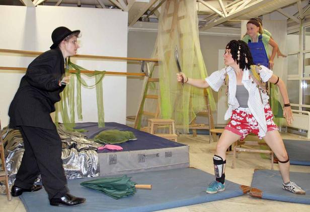 Eine Theaterszene mit einer Frau mit einem Messer und einer anderen im Anzug.