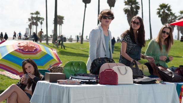 Auf einem Markt im Freien verkaufen junge Leute Handtaschen.