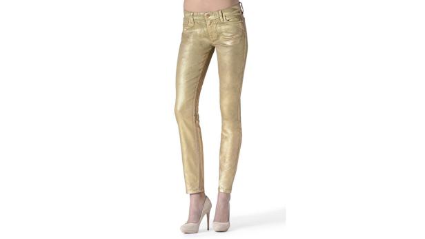 Eine Person trägt goldene Jeans und nudefarbene High Heels.