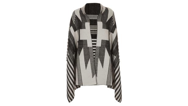 Ein Poncho mit geometrischen Mustern in Schwarz und Weiß vor einem weißen Hintergrund.