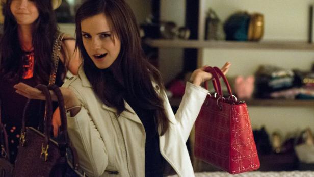 Emma Watson hält eine rote Handtasche in der Hand.