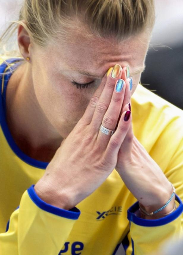Eine Frau in Sportkleidung hält die Hände vors Gesicht gesenkt.