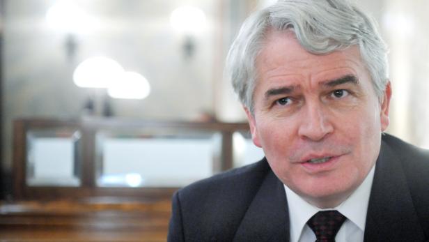 Ein Mann mit grauem Haar und dunklem Anzug blickt in die Kamera.