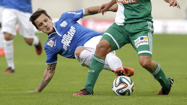 Zwei Fußballspieler kämpfen um den Ball auf dem Spielfeld.