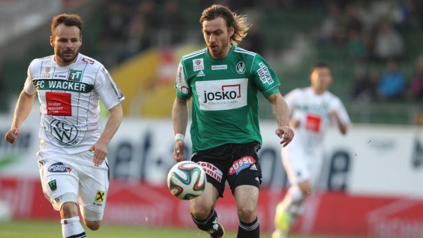 Ein Fußballspieler in Grün dribbelt den Ball während eines Spiels.