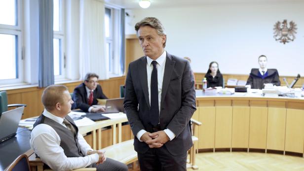 Ein Mann im Anzug steht in einem Gerichtssaal.