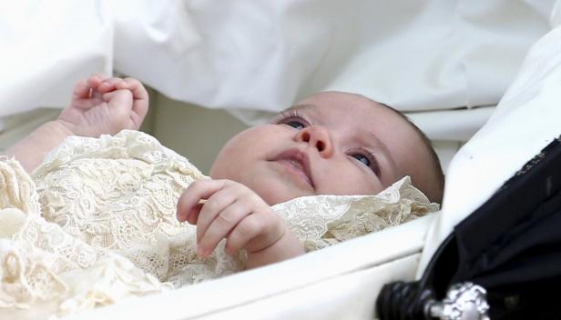 Ein Säugling liegt in einem Kinderwagen, bekleidet mit einem Spitzenkleid.