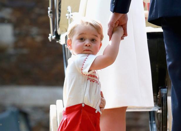 Prinz George hält die Hand eines Erwachsenen.