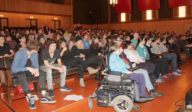 Ein Publikum sitzt in einem Auditorium und schaut auf die Bühne.