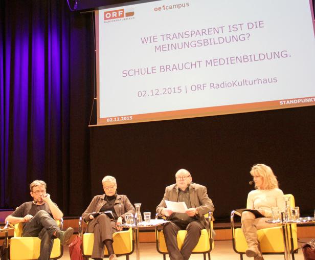 Vier Personen sitzen auf einer Bühne während einer Podiumsdiskussion zum Thema Medienbildung.