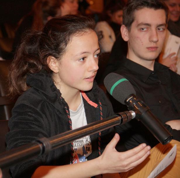 Ein junges Mädchen spricht bei einer Veranstaltung in ein Mikrofon.