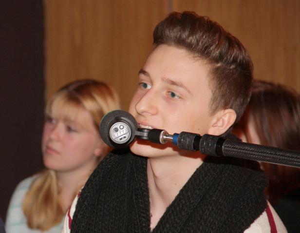 Ein junger Mann spricht in ein spezielles Mikrofon, das vor seinem Mund positioniert ist.