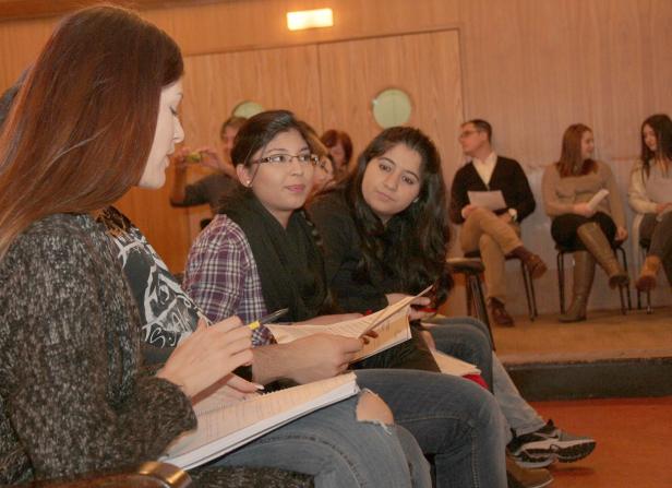 Mehrere junge Menschen sitzen in einem Raum und machen sich Notizen.