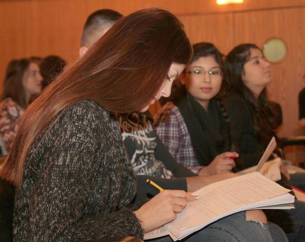 Eine junge Frau macht sich Notizen in einem Seminar oder einer Vorlesung.