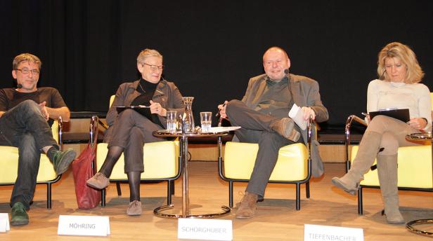 Vier Personen sitzen auf einer Bühne bei einer Podiumsdiskussion.
