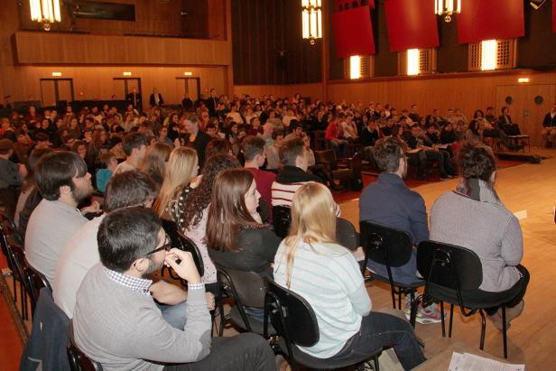 Ein Publikum sitzt in einem Theatersaal und schaut auf die Bühne.