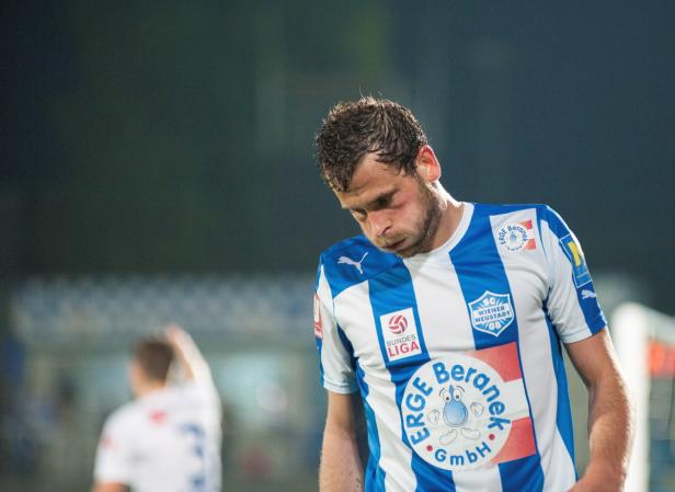 Ein Fußballspieler mit blau-weiß gestreiftem Trikot blickt nach unten.