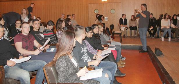 Ein Mann fotografiert eine Gruppe von Studenten in einem Hörsaal.