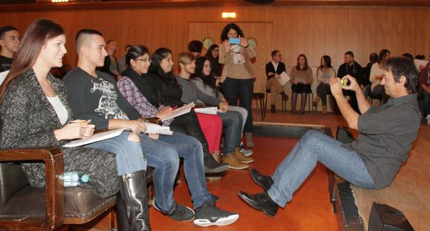 Ein Mann fotografiert mit seinem Smartphone eine Gruppe von Menschen in einem Raum.