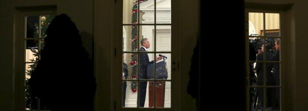 U.S. President Obama speaks about counter-terroris Barack Obama hält eine Rede vor einem Weihnachtsbaum, gesehen durch eine Fensterscheibe.