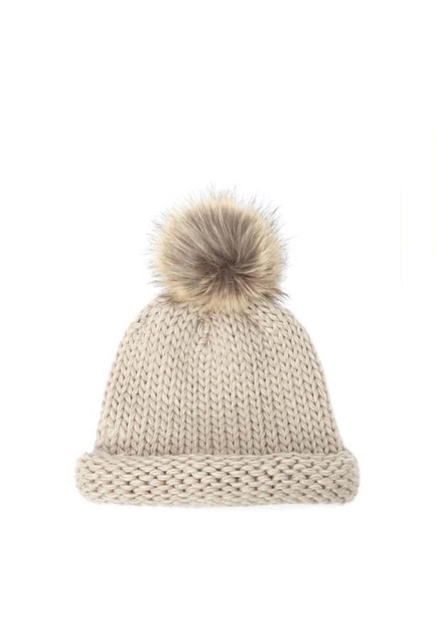 Eine beige Strickmütze mit einem großen Bommel.