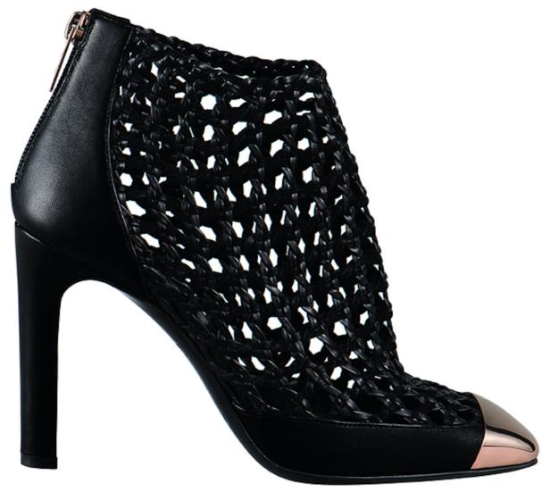 Ein schwarzer, hochhackiger Stiefelette mit geflochtenem Obermaterial und goldfarbener Spitze.