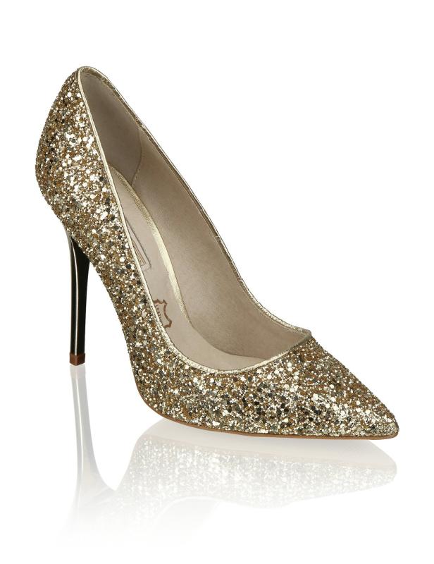 Ein goldener, glitzernder High Heel mit spitzer Zehe steht auf einem weißen Untergrund.