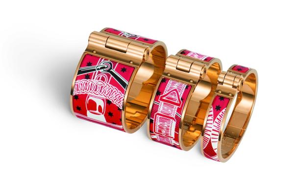 Vier goldene Armreifen mit roten, weißen und schwarzen Mustern liegen auf einem weißen Hintergrund.