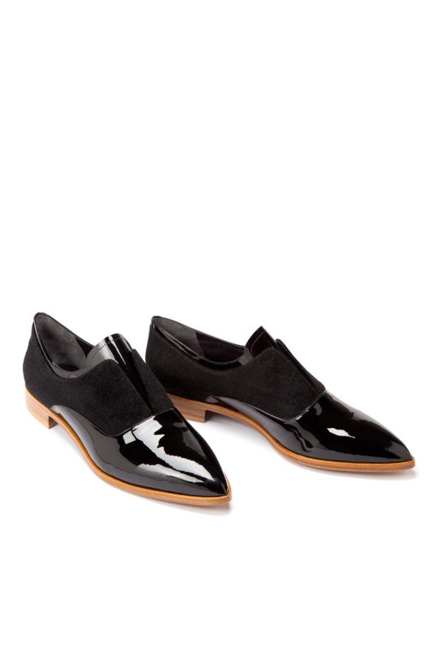 Zwei elegante, schwarze Lackschuhe mit spitzer Form stehen auf einem weißen Hintergrund.