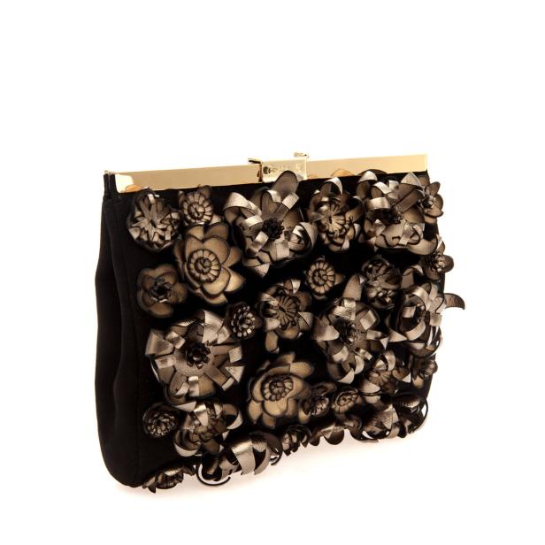 Eine schwarze Clutch mit goldenen Details und aufgenähten Blumen.