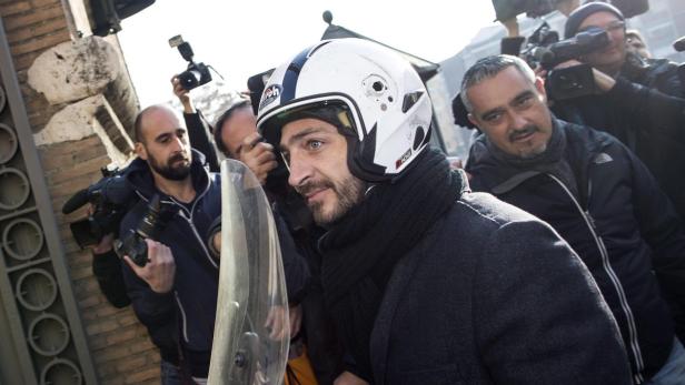 Ein Mann mit Motorradhelm wird von Fotografen umringt.