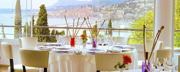 Ein gedeckter Tisch in einem Restaurant mit Blick auf eine Küstenstadt.