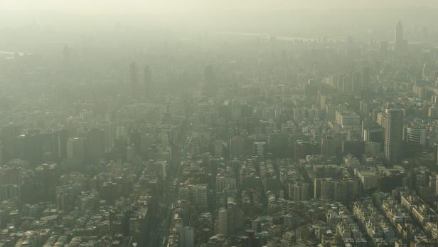 Luftaufnahme einer dicht bebauten Stadt unter einer Dunstglocke.