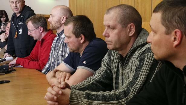 Eine Gruppe Männer sitzt an einem Tisch bei einer Pressekonferenz.