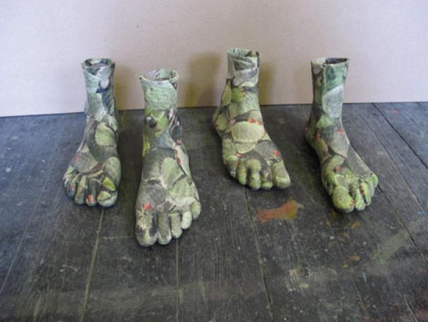 Vier skulpturale Füße mit Kaktusmuster stehen auf einem Holzboden.