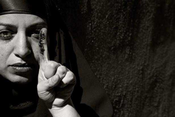 Eine Frau mit Kopftuch zeigt mit dem Finger auf etwas.